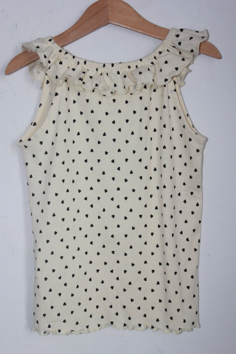 tweedehands creme mouwloze top met zwarte hartjes en een volant in maat 128 van monoprix. 100% bio-katoen